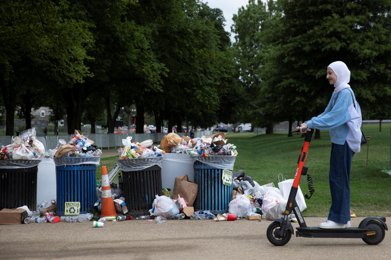 A visitor rides past overflowing trash from the previous evening's Independence Day fireworks celebration on the National Mall in Washington, U.S., July 5, 2022. REUTERS/Tom Brenner