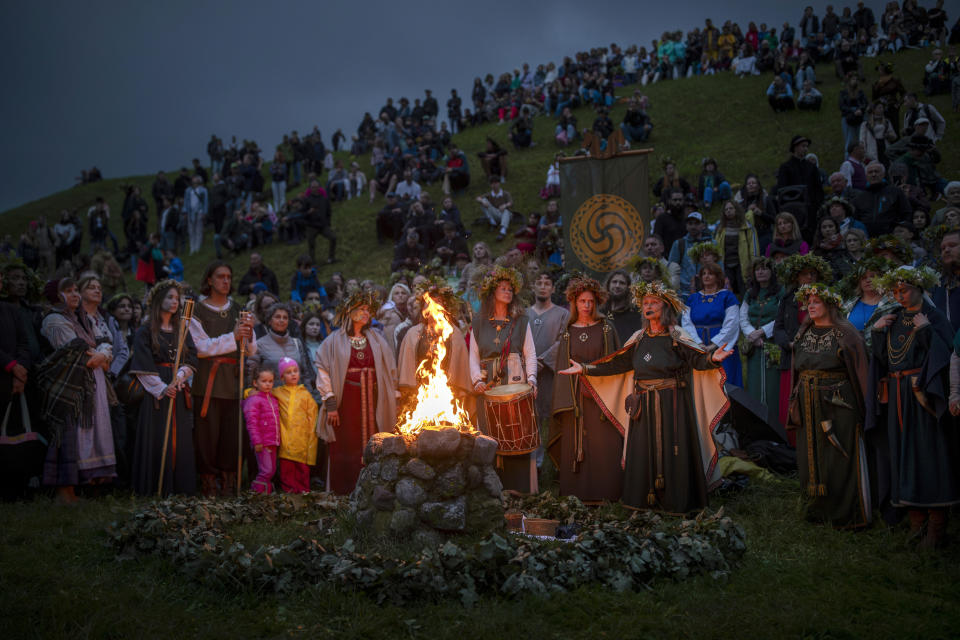 People wear traditional Lithuanian village-styled clothes as they celebrate Saint John's Day and the summer solstice in the small town of Kernave, some 35km (22 miles) northwest of the capital, Vilnius, Lithuania, Sunday, June 23, 2024. St. John's Day, or Midsummer Day, the shortest night of the year, is celebrated with festivities that include making oak leaf wreaths, leaping over flames, and encouraging young people to go out and look for fern flowers. (AP Photo/Mindaugas Kulbis)