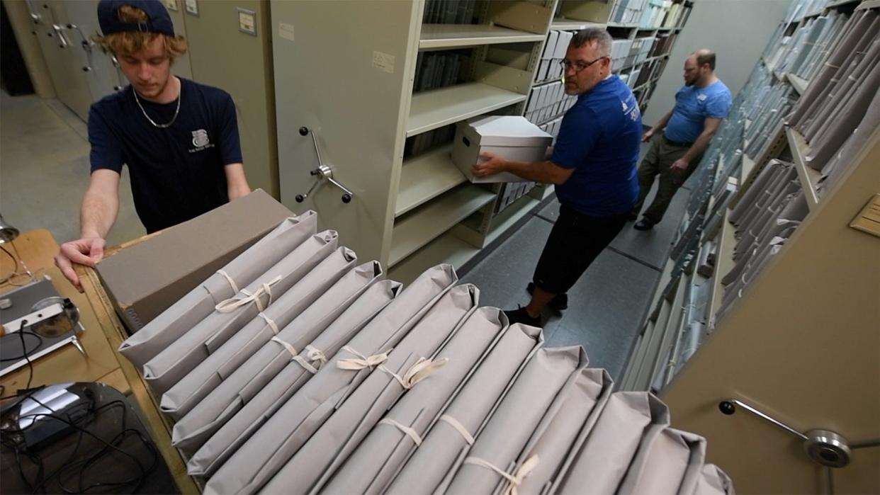 From the left, Peter Hamill and Michael Radzik of the Armstrong Relocation Company, and Adam Bent, assistant director of library and archives, work to pack archive materials from the East Market Street building on April 23.