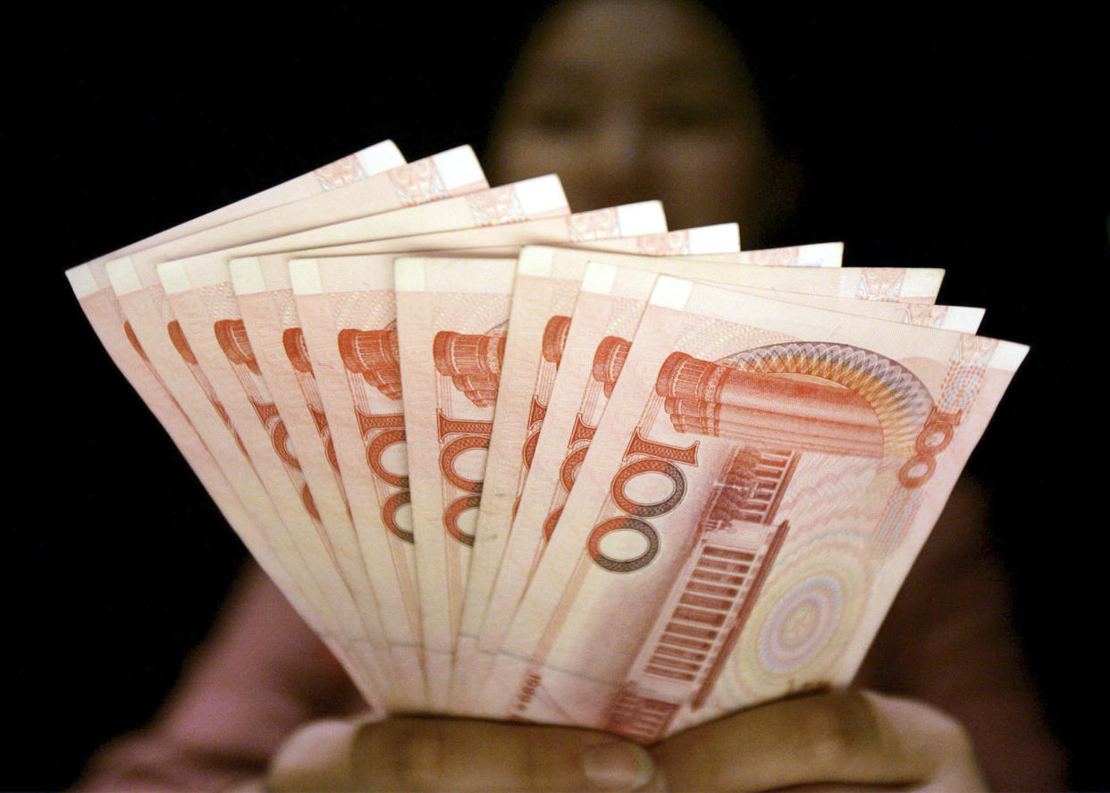 ** FILE ** In this July 22, 2005 file photo, a clerk at an foreign currency exchange desk at a hotel shows Chinese yuan banknotes in Shanghai, China. Beijing's currency has kept climbing Wednesday, June 18, 2008, with the official "parity rate" set at an all-time high against the U.S. dollar as U.S. and Chinese officials resumed talks centering on trade and other strategic issues. (AP Photo/Eugene Hoshiko, File)