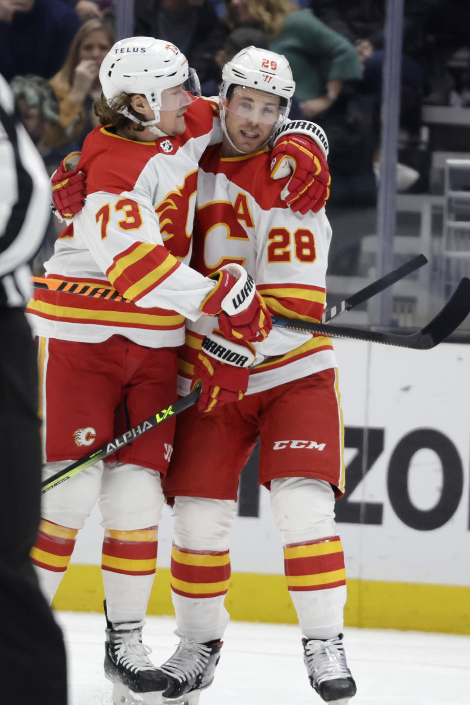 Calgary Flames right wing Tyler Toffoli (73) hugs center Elias Lindholm (28) after Lindholm scored against the Seattle Kraken during the first period of an NHL hockey game Friday, Jan. 27, 2023, in Seattle. (AP Photo/John Froschauer)