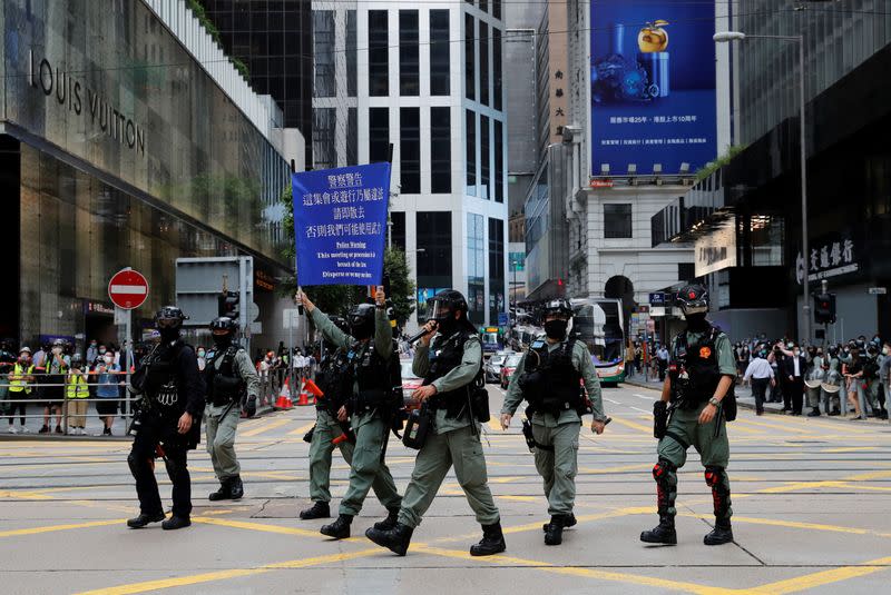 Riot police raise a warning flag as they disperse anti-government demonstrators at Central District against the second reading of a controversial national anthem law in Hong Kong