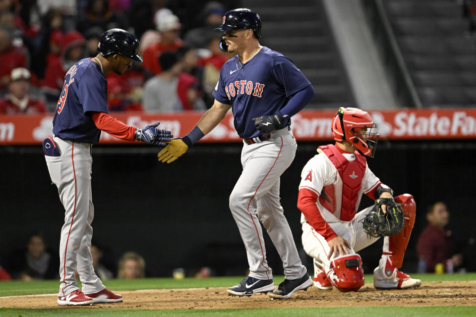 Boston Red Sox's Ceddanne Rafaela, left, greets Reese McGuire, next to Los Angeles Angels catcher Logan O'Hoppe, after McGuire hit a two-run home run during the second inning of a baseball game in Anaheim, Calif., Friday, April 5, 2024. (AP Photo/Alex Gallardo)
