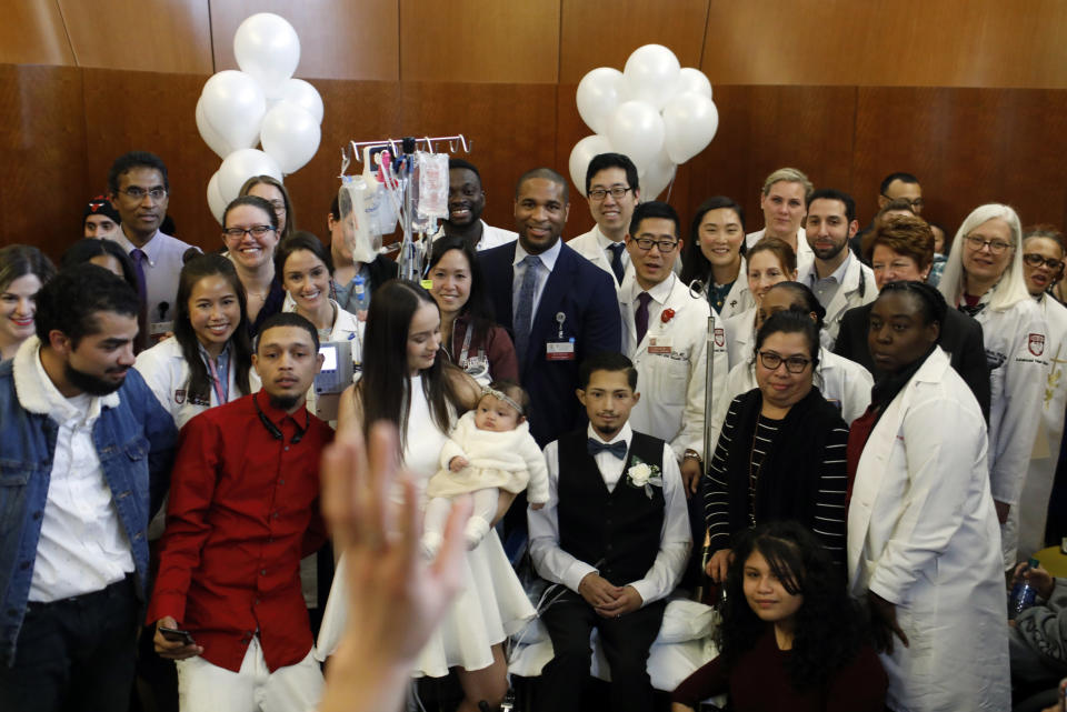 In this Wednesday, Nov. 27, 2019 photo, Javier Rodriguez and Crystal Cuevas hold their four-month-old daughter Leia as they pose with medical staff following their wedding at the University of Chicago Medical Center for Care and Discovery in Chicago. Rodriguez, 23, who received two heart transplants as a teenager died in hospice care, days after he married his high school sweetheart, his new bride said. (Brian Cassella/Chicago Tribune via AP)