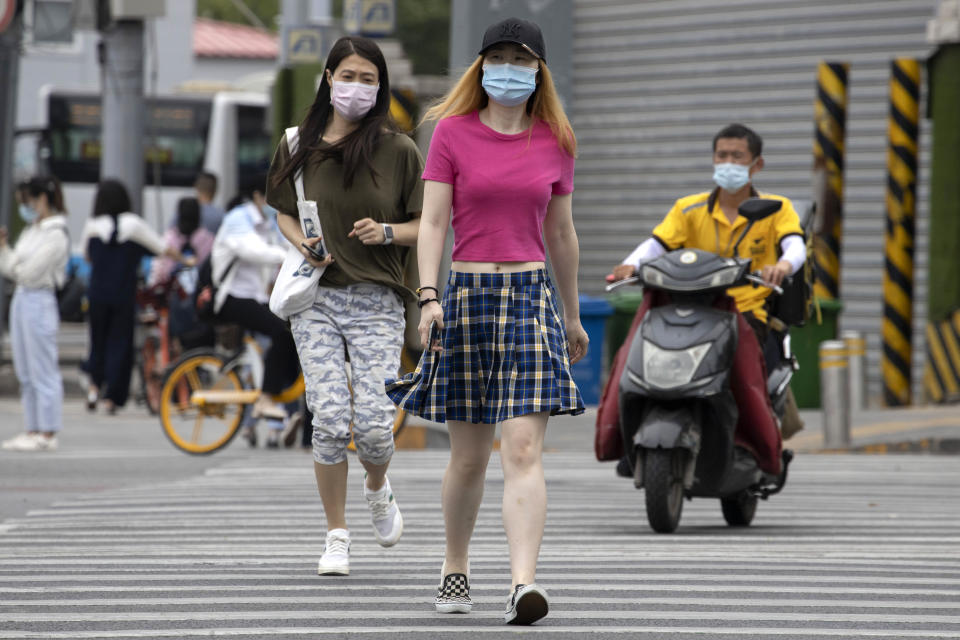 Varias personas que portan mascarillas para protegerse del coronavirus cruzan una avenida el miércoles 17 de junio de 2020, en Beijing. (AP Foto/Ng Han Guan)