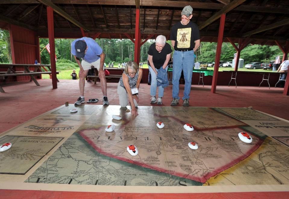 Wendy Bawabe, second from left, points out areas of Norwell on a new copy of the Walling Map of Plymouth County in 1857. The map was shown at Stetson Heritage Day, Saturday, Aug. 19, 2023.