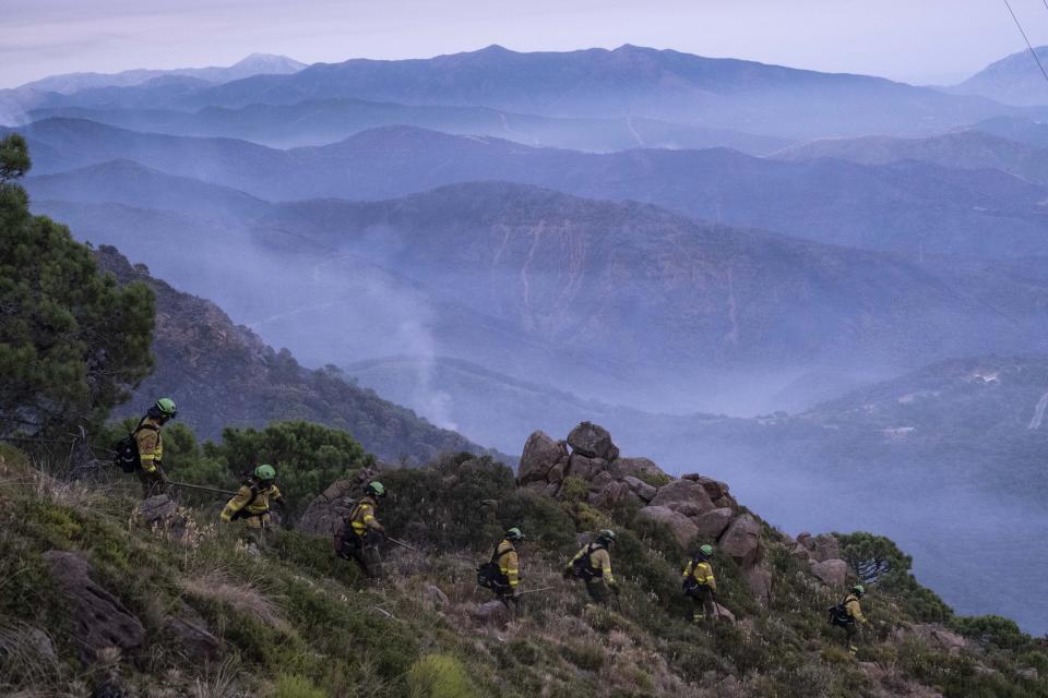 Forest firefighters work in a wildfire near the town of Jubrique, in Malaga province, Spain, Saturday, Sept. 11, 2021. Firefighting crews in southern Spain are waiting for much-needed rainfall expected on Monday that they hope can help extinguish a stubborn mega-fire that has ravaged 7,400 hectares (18,300 acres) in five days and displaced some 3,000 people from their homes. (AP Photo/Pedro Armestre)