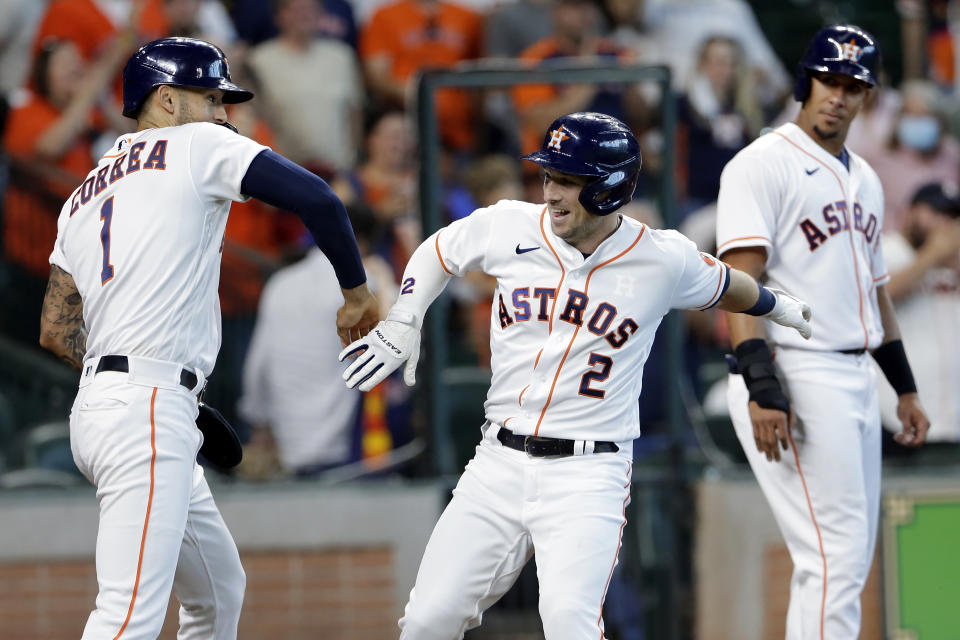 Houston Astros' Carlos Correa (1) and Alex Bregman (2) celebrate as Michael Brantley (23) looks on after they all scored on a three-run home run by Bregman during the third inning of a baseball game against the Los Angeles Angels, Saturday, April 24, 2021, in Houston. (AP Photo/Michael Wyke)