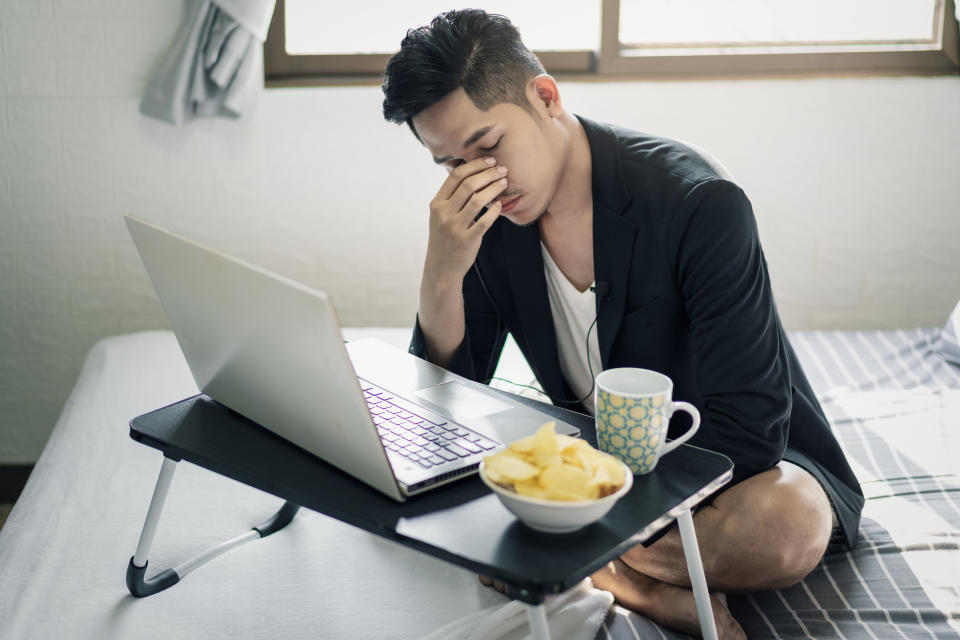 Handsome young Asian businessman sitting down using the laptop for video call while working from home