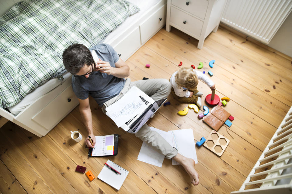 parent working on floor as child plays with toys next to them