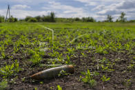 FILE - An unexploded shell lies in a field in Cherkaska Lozova, outskirts of Kharkiv, eastern Ukraine, on May 28, 2022. Ukraine is one of the world's largest exporters of wheat, corn and sunflower oil, but the war and a Russian blockade of its ports have halted much of that flow, endangering world food supplies. As food costs and fuel bills soar, inflation is plundering people’s wallets, sparking a wave of protests and workers’ strikes around the world. (AP Photo/Bernat Armangue)