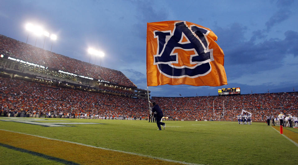 In this Sept. 6, 2014 photo, an Auburn cheerleader runs across the field with a flag after a touchdown during the first half of an NCAA college football game against San Jose State in Auburn, Ala. Ahead of the 2014 college football season, the AP asked its panel of Top 25 voters, who are known for ranking the nation's top teams each week, to weigh in on which stadium had the best game day atmosphere. Auburn’s Jordan-Hare received recognition from the panel. (AP Photo/Butch Dill, File)