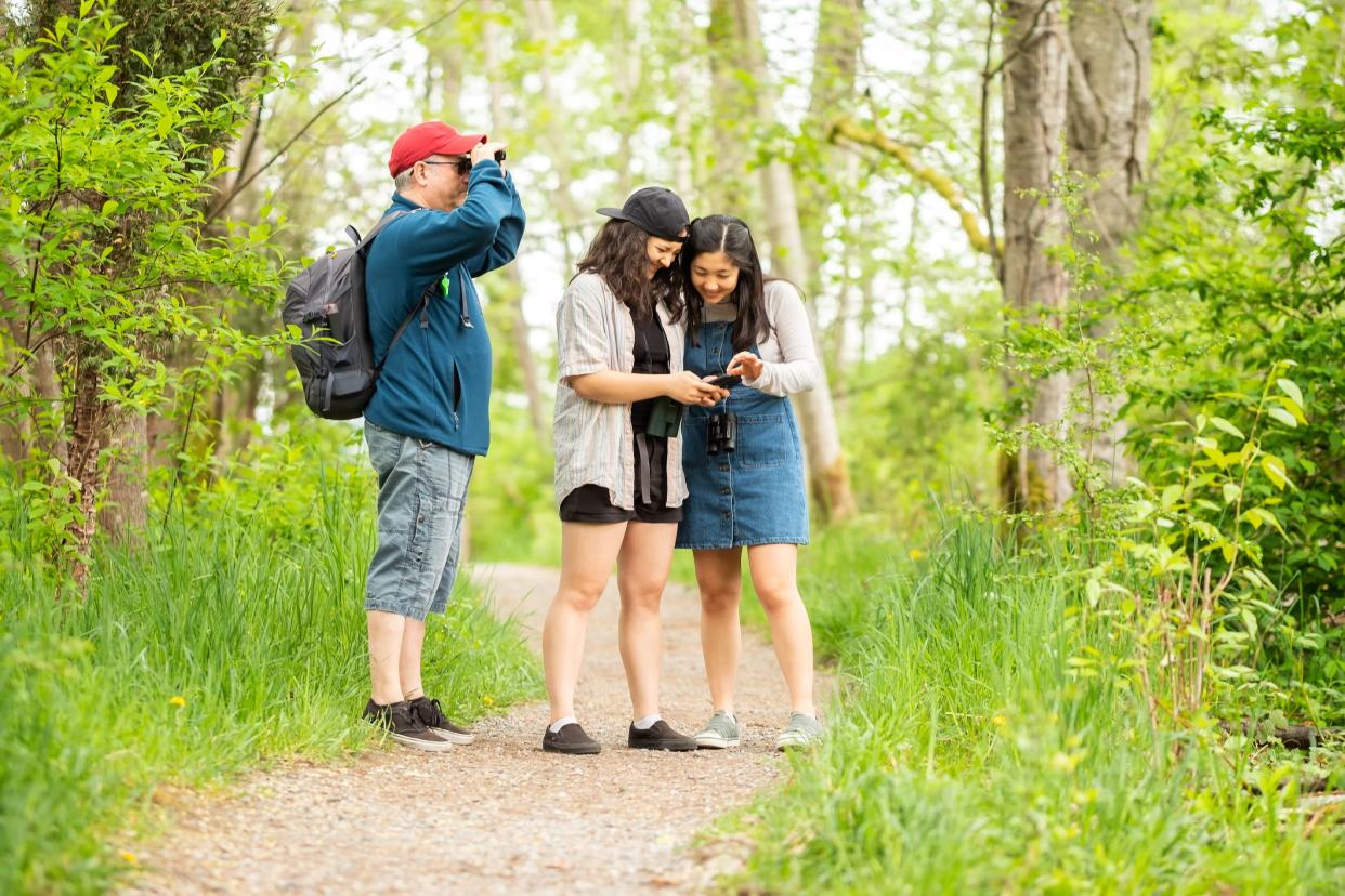 Multi-racial, 2 generation family birdwatching in forest.  North Vancouver, British Columbia, Canada