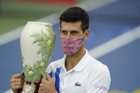 Novak Djokovic, of Serbia, front, holds his winning trophy after winning his match with Milos Raonic, of Canada, at the Western & Southern Open tennis tournament Saturday, Aug. 29, 2020, in New York. (AP Photo/Frank Franklin II)