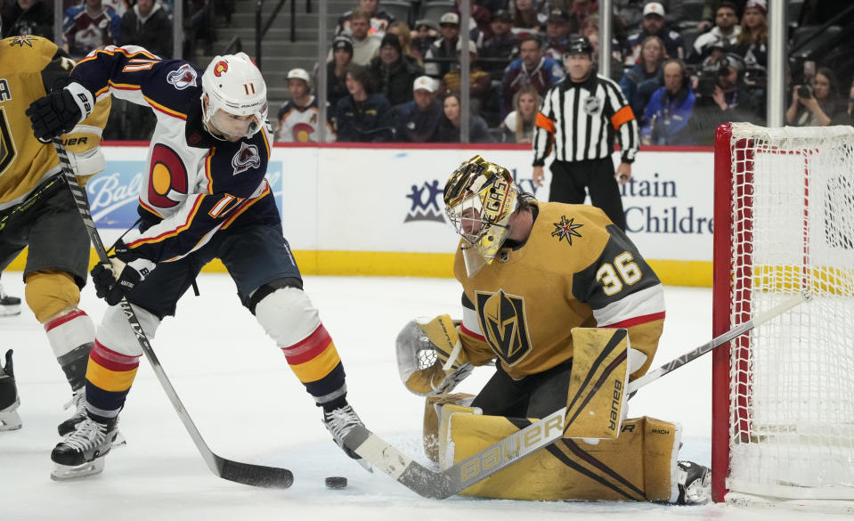 Colorado Avalanche center Andrew Cogliano, left, redirects the puck at Vegas Golden Knights goaltender Logan Thompson in the third period of an NHL hockey game, Monday, Jan. 2, 2023, in Denver. (AP Photo/David Zalubowski)