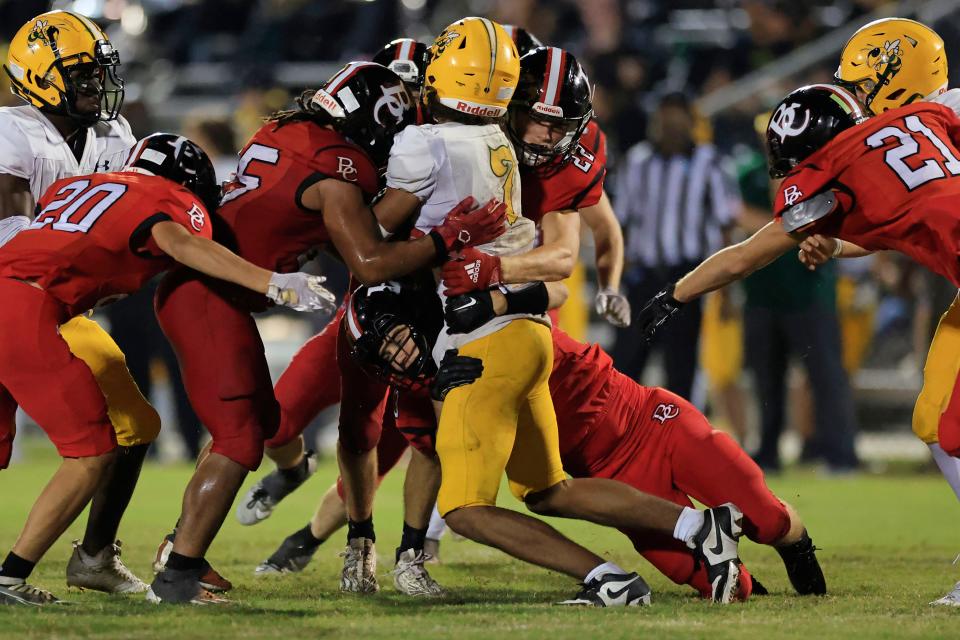 Baker County's Hudson Hodges (23), bottom, wraps up the legs of Yulee's Tyson Wharton (7) as Baker County's Benny Lewis (25), left, and Kale Crews (22) wrap up with his torso on a tackle.