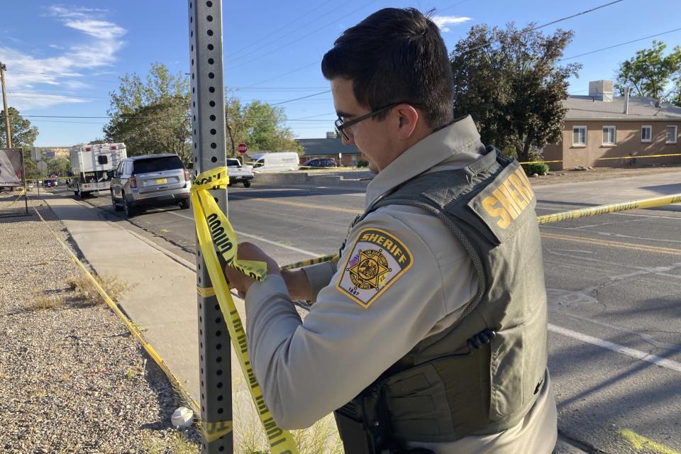 A San Juan County sheriff's deputy cordons off a road following a deadly shooting Monday, May 15, 2023, in Farmington, N.M. (AP Photo/Susan Montoya Bryan)