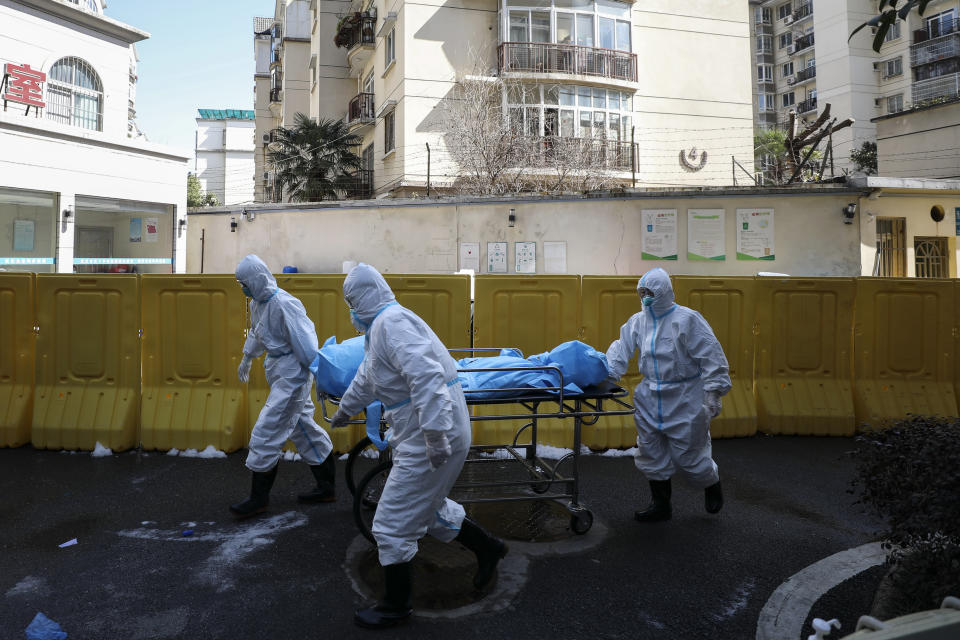 In this Sunday, Feb. 16, 2020, photo, medical workers move a person who died from COVID-19 at a hospital in Wuhan in central China's Hubei province. Chinese authorities on Monday reported a slight upturn in new virus cases and hundred more deaths for a total of thousands since the outbreak began two months ago. (Chinatopix via AP)