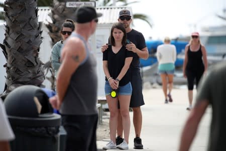 People pause to look over a makeshift memorial near Truth Aquatics as the search continues for those missing in a pre-dawn fire that sank a commercial diving boat near Santa Barbara, California