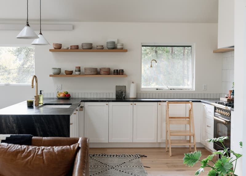 Ceramic dishware neatly stacked on open shelves in kitchen.