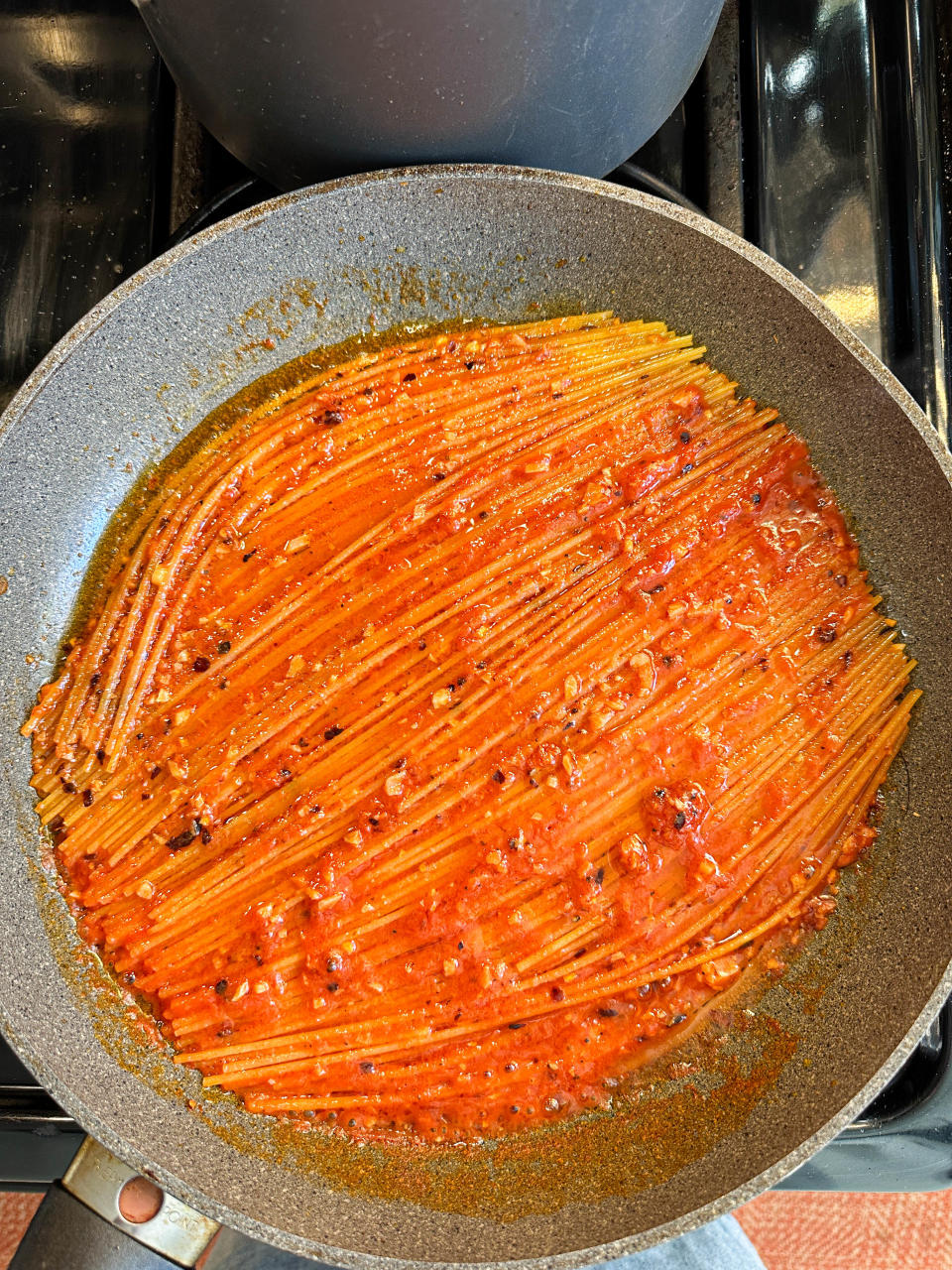 Spaghetti noodles cooking in sauce in a pan