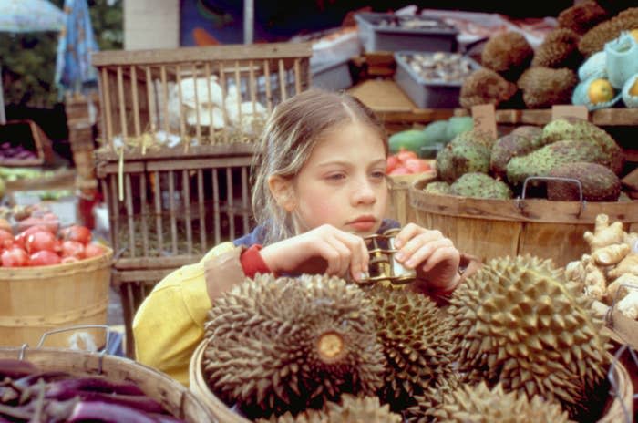 Michelle Trachtenberg spies from behind a barrel of fruit