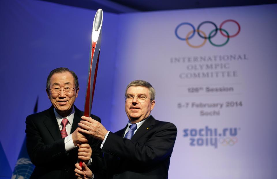 United Nations Secretary-General Ban Ki-moon, left, is presented with an Olympic torch by International Olympic Committee President Thomas Bach, right, after Ban addressed the IOC's general assembly ahead of the upcoming 2014 Winter Olympics, Thursday, Feb. 6, 2014, in Sochi, Russia. It was the first time a U.N. secretary-general delivered a keynote address to the IOC's general assembly. (AP Photo/David Goldman)