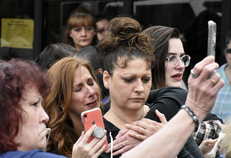 In this March 19, 2020, photo, Fairmont Regional Medical Center employees Carrin Powell, left, embraces Michele Myers-Stone, during a vigil at the hospital’s closing in Fairmont, W.Va. The coronavirus pandemic couldn't come at a worse time for communities trying to cope after a wave of hospital shutdowns across the rural United States. (Tammy Shriver/Times-West Virginian via AP)