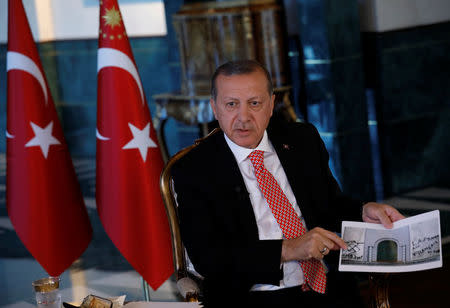 Turkish President Tayyip Erdogan shows a picture as he attends an interview with Reuters at the Presidential Palace in Ankara, Turkey, April 25, 2017. REUTERS/Umit Bektas