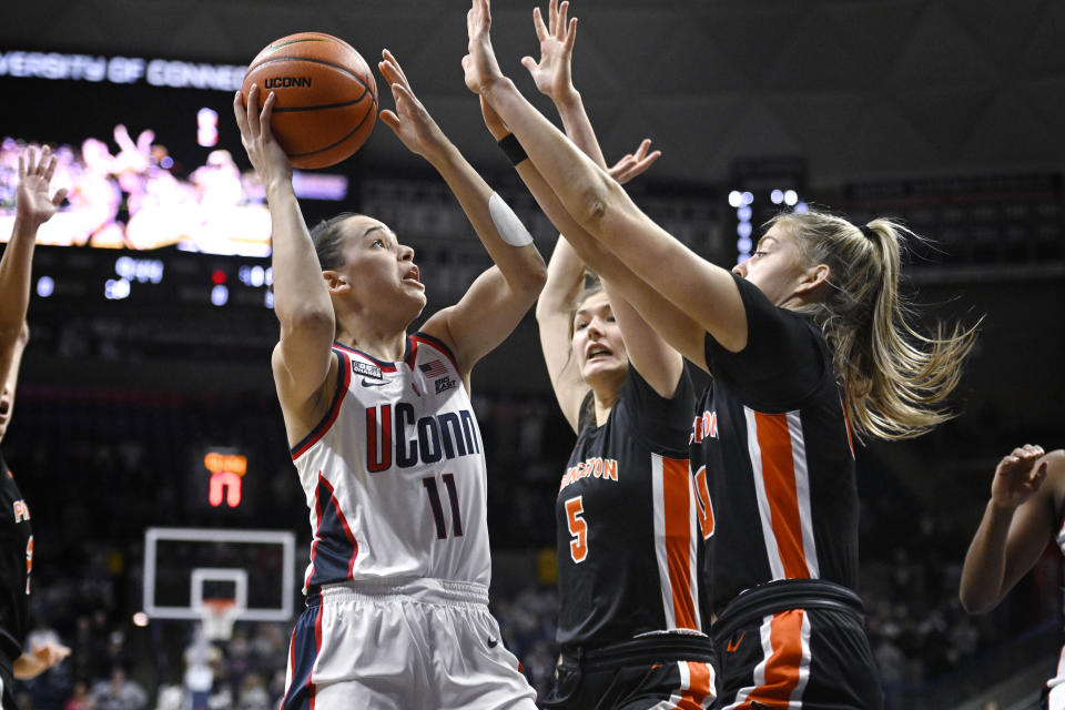 Connecticut's Lou Lopez-Senechal, left, shoots as Princeton's Paige Morton, center, and Ellie Mitchell defend during the first half of an NCAA college basketball game Thursday, Dec. 8, 2022, in Storrs, Conn. (AP Photo/Jessica Hill)