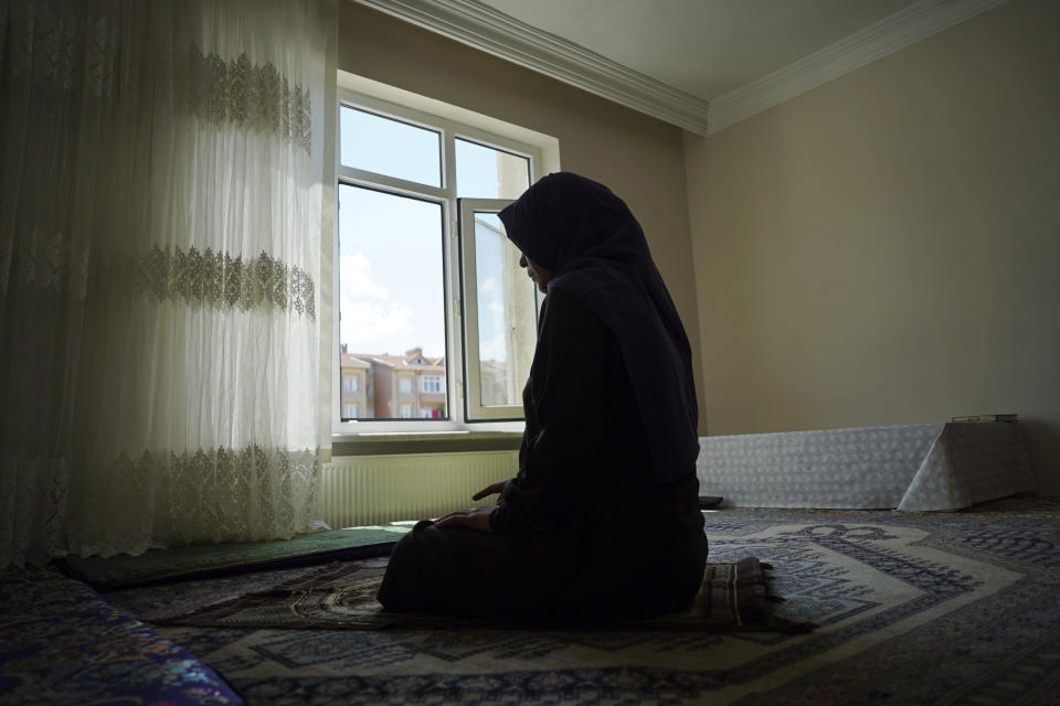 In this Aug. 20, 2018, photo, Meripet, 29, prays at her home in Istanbul, Turkey. Meripet came to Turkey in February 2017 to visit her sick father, leaving four children behind. While in Turkey, she heard Uighur passports were being seized and that people who had gone abroad were being taken to reeducation, so she stayed in Turkey, giving birth to Abduweli. She hasn't seen her other four children since, and heard they were taken to a live-in kindergarten in Hotan, China. (AP Photo/Dake Kang)