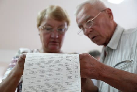 Voters look through a ballot at a polling station during Ukraine's parliamentary election in Kiev