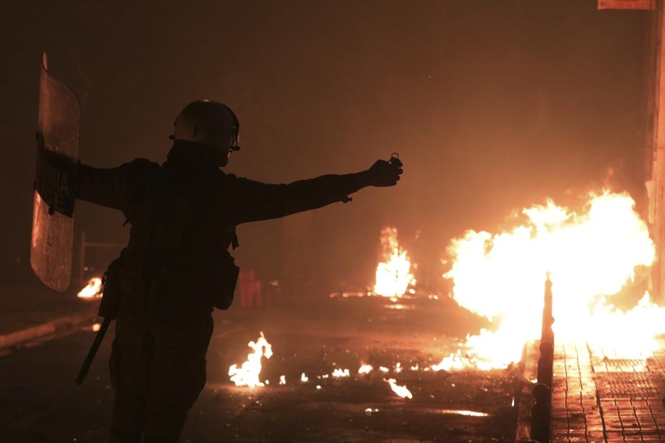 A riot policeman raises his hands up as a petrol bomb explodes near to him during clashes in the Athens neighborhood of Exarchia, a haven for extreme leftists and anarchists, Saturday, Nov. 17, 2018. Clashes have broken out between police and anarchists in central Athens on the 45th anniversary of a student uprising against Greece's then-ruling military regime. (AP Photo/Yorgos Karahalis)