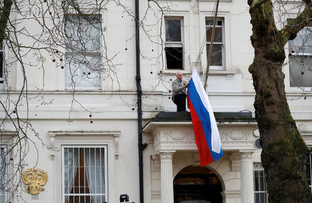 A man takes the flag off the flagpole outside the consular section of Russia's Embassy in London, Britain, March 14, 2018. REUTERS/Phil Noble