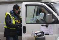 A protester speaks with a police officer as he distributes a notice, Wednesday, Feb. 16, 2022 in Ottawa. Ottawa’s police chief was ousted Tuesday amid criticism of his inaction against the trucker protests that have paralyzed Canada's capital for over two weeks, while the number of blockades maintained by demonstrators at the U.S. border dropped to just one. (Adrian Wyld /The Canadian Press via AP)