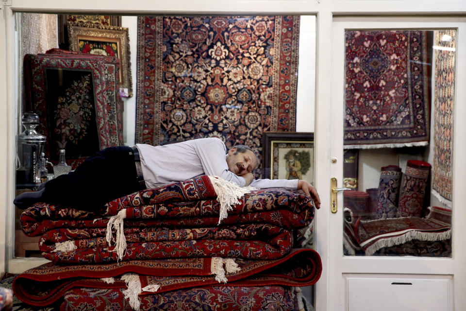 Un vendedor de alfombras duerme la siesta en el antiguo bazar de Teherán, Irán, 23 de julio de 2018. Estados Unidos anunció nuevas sanciones a Irán el miércoles 11 de diciembre de 2019. (AP Foto/Ebrahim Noroozi)