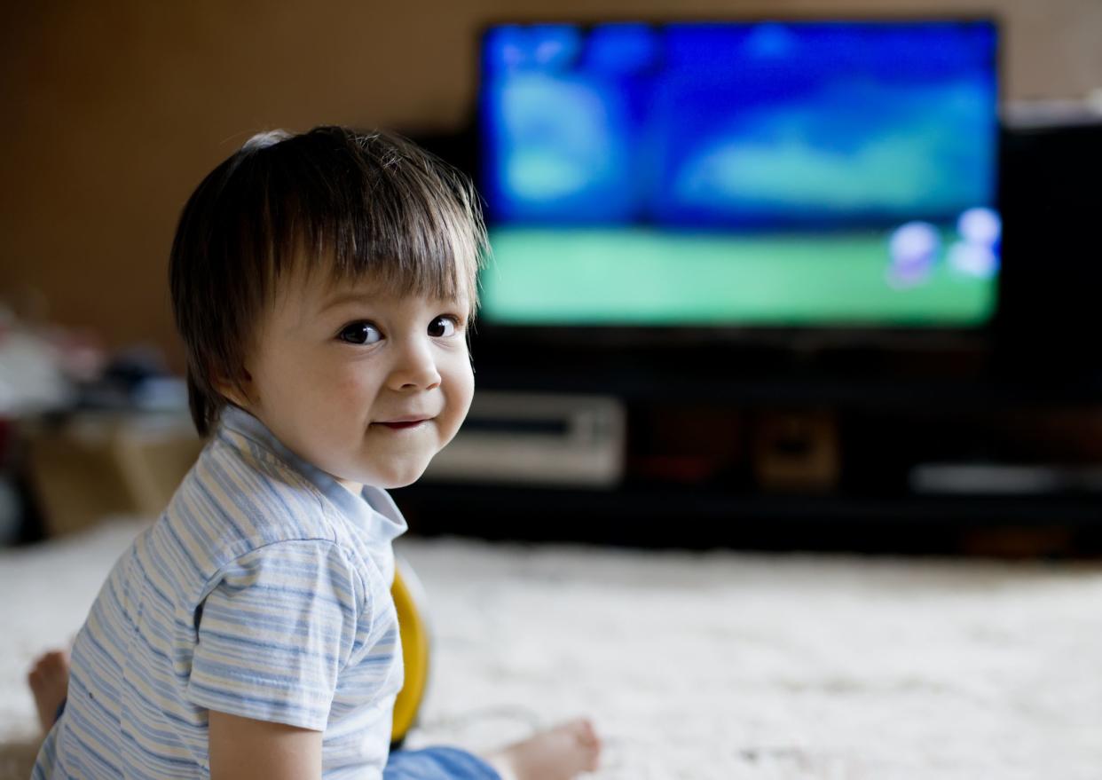 Little boy sitting on carpet and looking TV