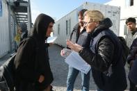 Employees of France's 'Department for Social Cohesion and Protection of the Population' distribute documents to migrants on the "Jungle" camp's demolition at a reception centre in Calais, northern France, on October 23, 2016