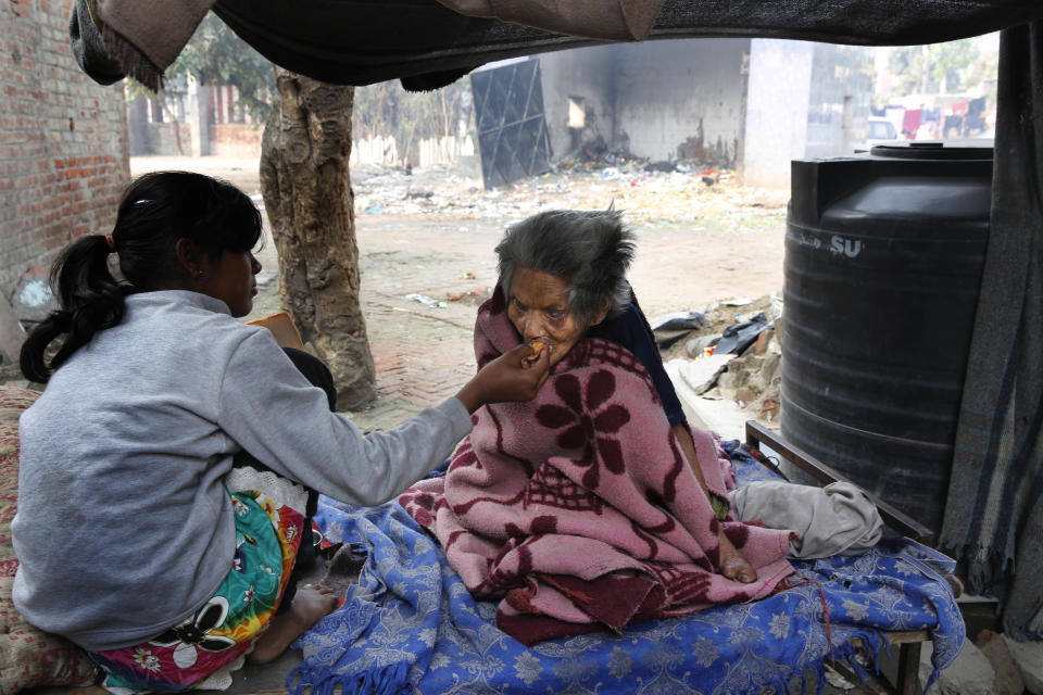 In this Feb. 20, 2014 photo, an Indian girl feeds her leprosy-affected grandmother at a leper colony in New Delhi, India. The stigma of leprosy endures in India, even though the country has made great strides against the disease, which is neither highly contagious nor fatal. Now the number of new annual cases has risen slightly after years of steady decline, and medical experts say the enormous fear surrounding leprosy is hindering efforts to finally eliminate it. (AP Photo/Manish Swarup)