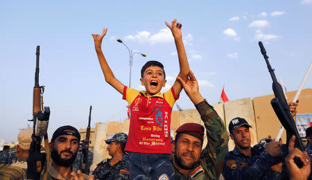 Members of Iraqi Federal Police carry a boy as they celebrate victory of military operations against the Islamic State militants in West Mosul, Iraq July 2, 2017. REUTERS/Erik De Castro