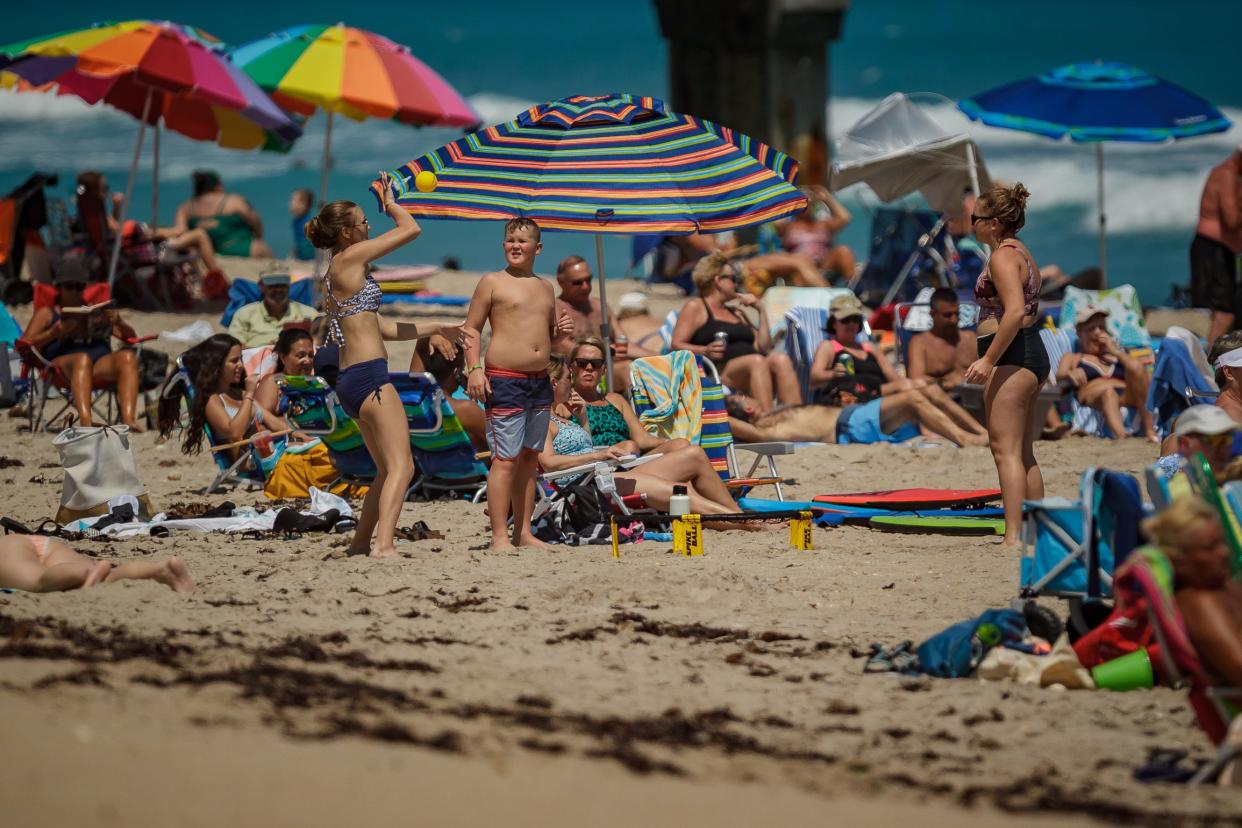 Beachgoers sun themselves and play games on the beachfront at Lake Worth Beach Park in Lake Worth Beach, Fla., on Wednesday, March 24, 2021.