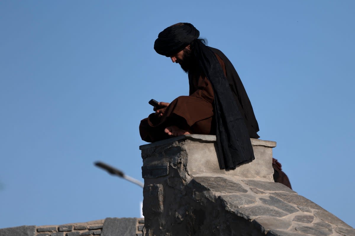 A Taliban fighter uses his phone at Wazir Akbar Khan in Kabul (Getty)