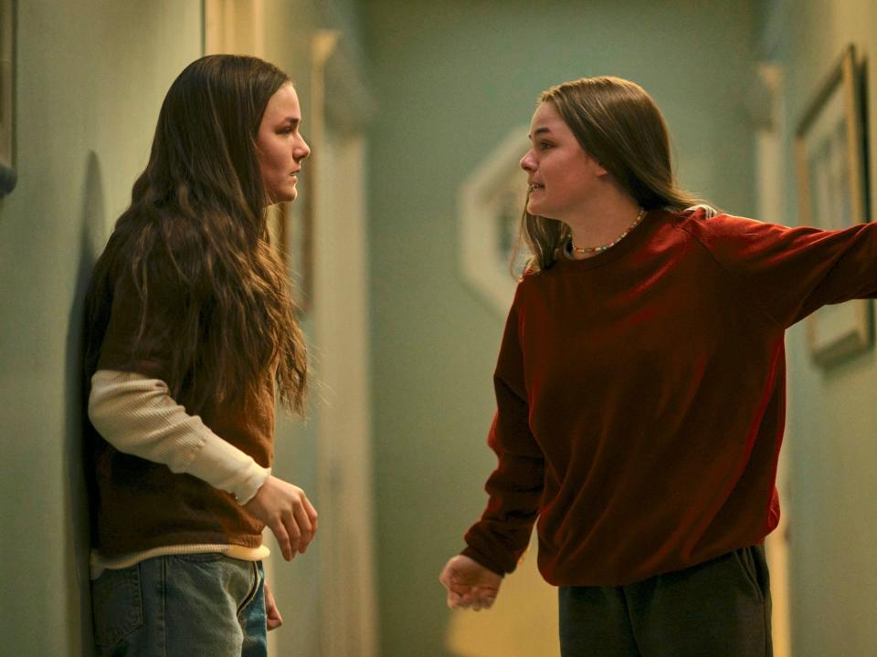 Twin girls arguing in a hallway.