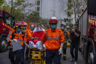 Ambulance staff attend a patient nearby the fire site in Cheung Sha Wan, a residential and industrial area , in Hong Kong, Friday, March 24, 2023. Hong Kong firefighters were battling a blaze Friday at a warehouse that forced more than 3,000 people to evacuate, including students, police said. (AP Photo/Louise Delmotte)