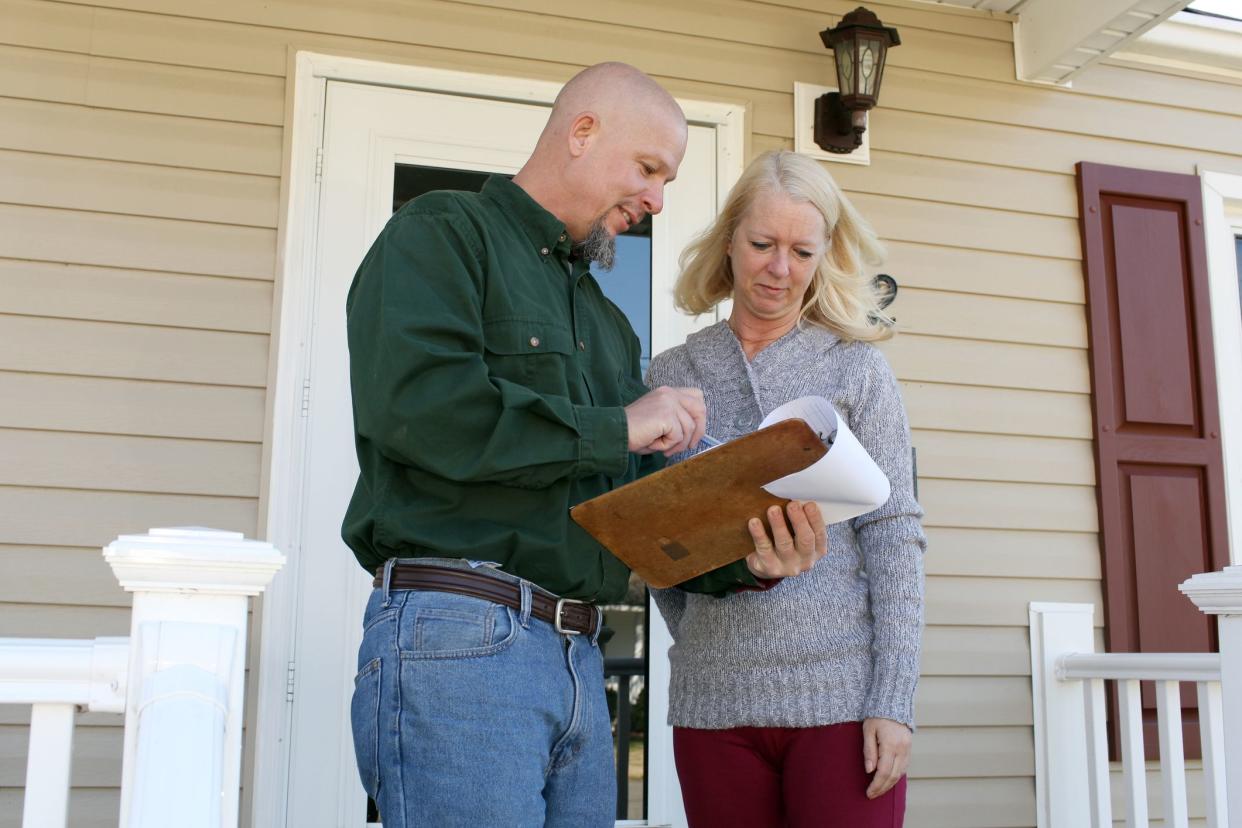 home inspector going over paperwork with woman owner of suburban home on her front porch