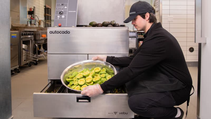 A Chipotle employee gathers the pitted and peeled avocado from the bottom of the new “Autocado” machine developed by company Vebu, in this photo released by the restaurant. 