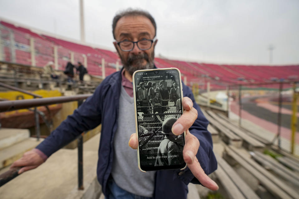 FILE - Sergio Munoz shows a photo of when he was detained in the National Stadium, which was used as a prison and place of torture, and where he was detained on Sept. 1973, in Santiago, Chile, Saturday, Sept. 2, 2023. Muñoz, who was 25 years old when he was taken to the stadium by the dictatorship, said he felt horror when a hooded person walked among the inmates to identify adversaries of the new regime. “There was a snitch who wore a black hood and identified others. That person was taken out, interrogated, and did not come back,” said Muñoz. (AP Photo/Esteban Felix, File)