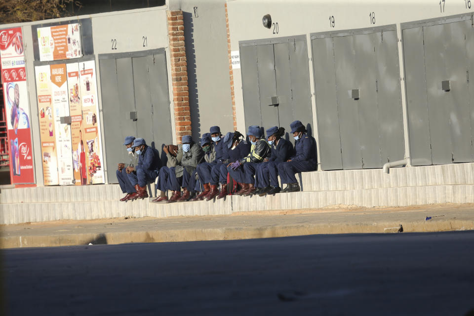 Zimbabwean police take a break at the side of a street in Harare, Friday, July, 31, 2020. Zimbabwe's capital, Harare, was deserted Friday, as security agents vigorously enforced the country's lockdown amidst planned protests. Police and soldiers manned checkpoints and ordered people seeking to get into the city for work and other chores to return home. (AP Photo/Tsvangirayi Mukwazhi)