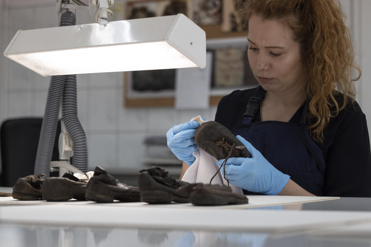 A worker rubs away dust on a shoe that belonged to a child victim of the former Nazi German death camp Auschwitz-Birkenau at the conservation laboratory on the grounds of the camp in Oswiecim, Poland, Wednesday, May 10, 2023. The museum is able to conserve about 100 shoes a week, and has processed 400 since the project began last month. The aim is not to restore them to their original state but to render them as close to how they were found at war's end as possible. (AP Photo/Michal Dyjuk)