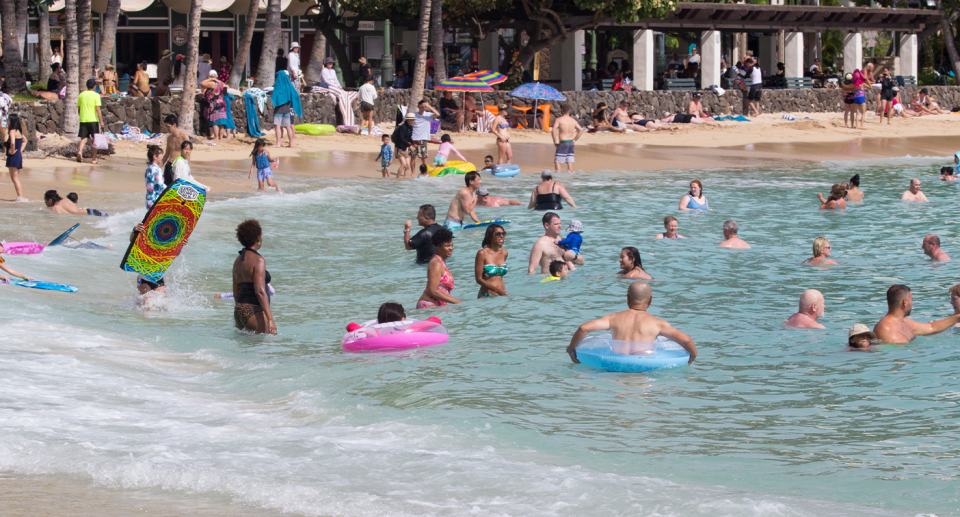 Tourists in the water in front of hotels in Hawaii.
